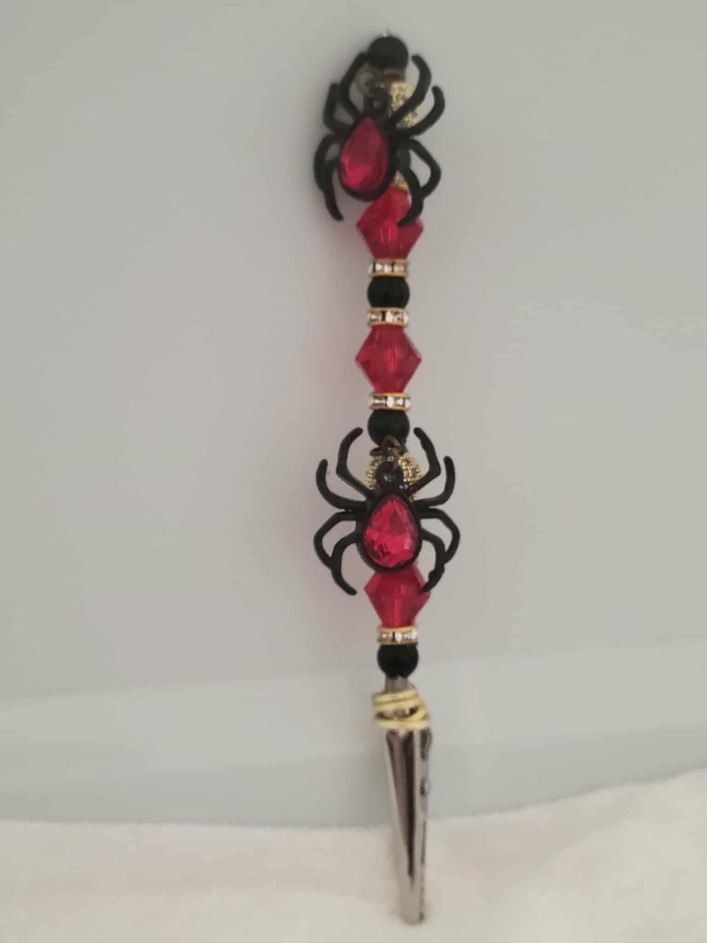Decorative joint holder. This handcrafted roach clip is crawling with red and black shimmering gems and double black widow charms, each with a red jeweled stone in the center.