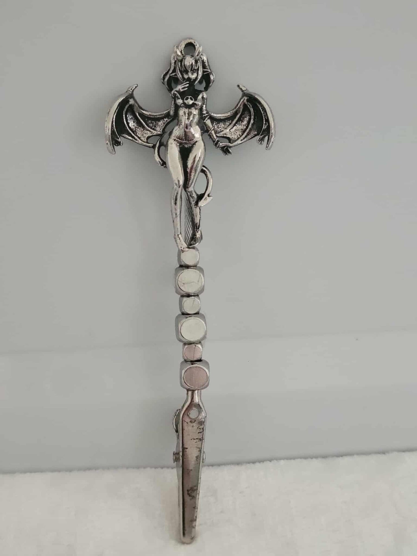 Decorative joint holder. Sexy demon girl roach clip. Demoness charm of a partially naked girl with horns on the top of her hair, she has silver bat like wings with a devil like tail whipped around her along with sleek silver cube beads.