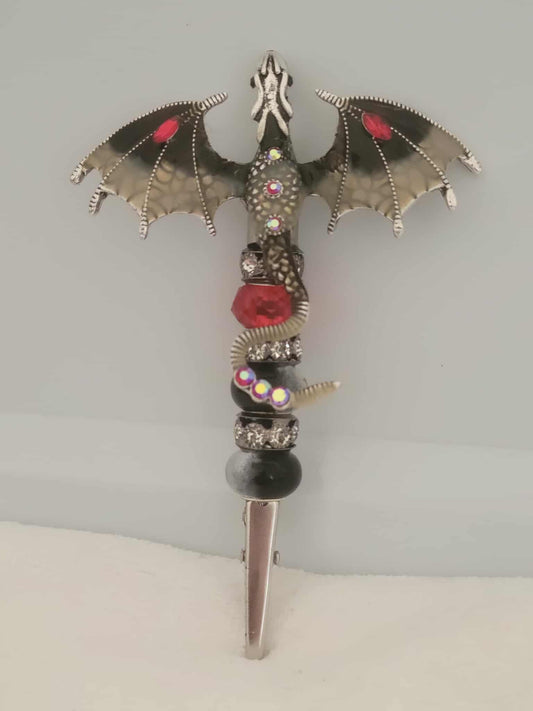 Decorative joint holder. Black and grey dragon roach clip with red jewels on the wings and black beaded handle with a single glass red bead with black rhinestone spacer beads.