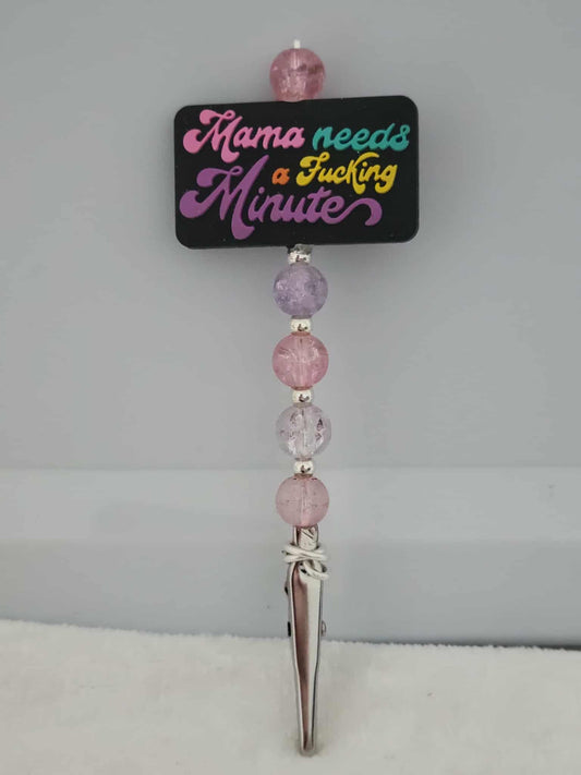 Decorative joint holder. Roach clip with a silicone bead with pink, teal, purple, and yellow words that says, “Mama needs a f*cking minute,” along with pastel-pink and lavender beads and small silver spacers.