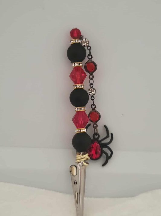  Decorative joint holder. Sultry roach clip with rich blood-red gems, matte black beads, and a dangling jeweled spider.
