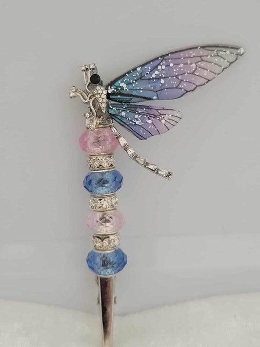 Decorative joint holder. Silver dragonfly roach clip with shimmering pink and blue ombre wings with pink and blue cotton candy like colored beads with rhinestone spacer beads.