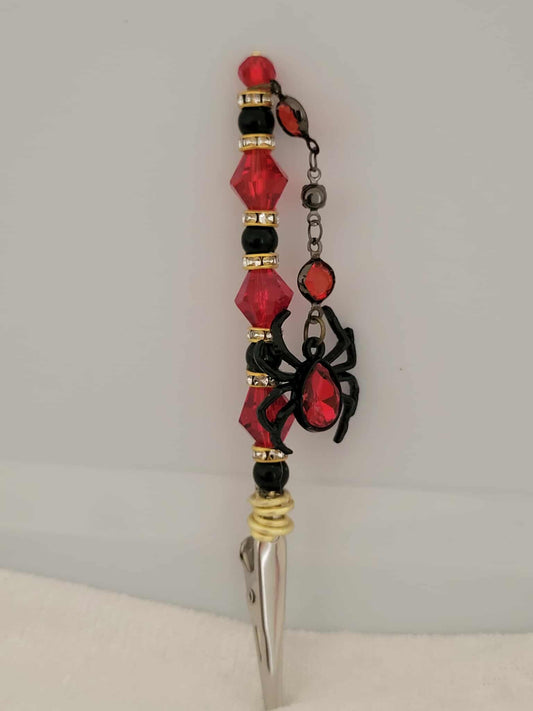 Decorative joint holder. Sultry red and black roach clip, featuring a dangling rhinestone spider charm and blood-red faceted beads.