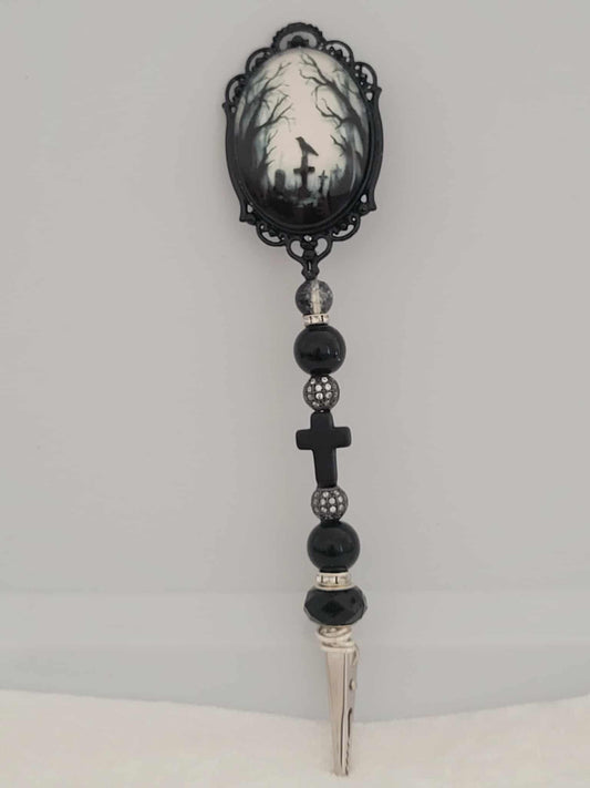 Decorative joint holder. Gothic handcrafted roach clip featuring a gothic cameo centerpiece of a graveyard scene including gravestones, crosses, black crows and spooky forest. With dark faceted beads, shimmering black rhinestone spacers, and a matte cross bead.