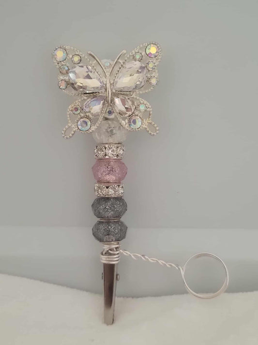 Decorative joint holder. Sparkling crystal butterfly roach clip with pink glitter-dipped beads, and a sleek silver beaded grip. There is a metal ring extending from right above the roach clip and below the start of the beads. This allows users to wear the ring on their finger that holds the roach clip allowing the user to hold other objects like your phone or a video game controller.  The ring is not adjustable and was made to be worn as a midi-ring, about a midi ring size 3 (14mm).
